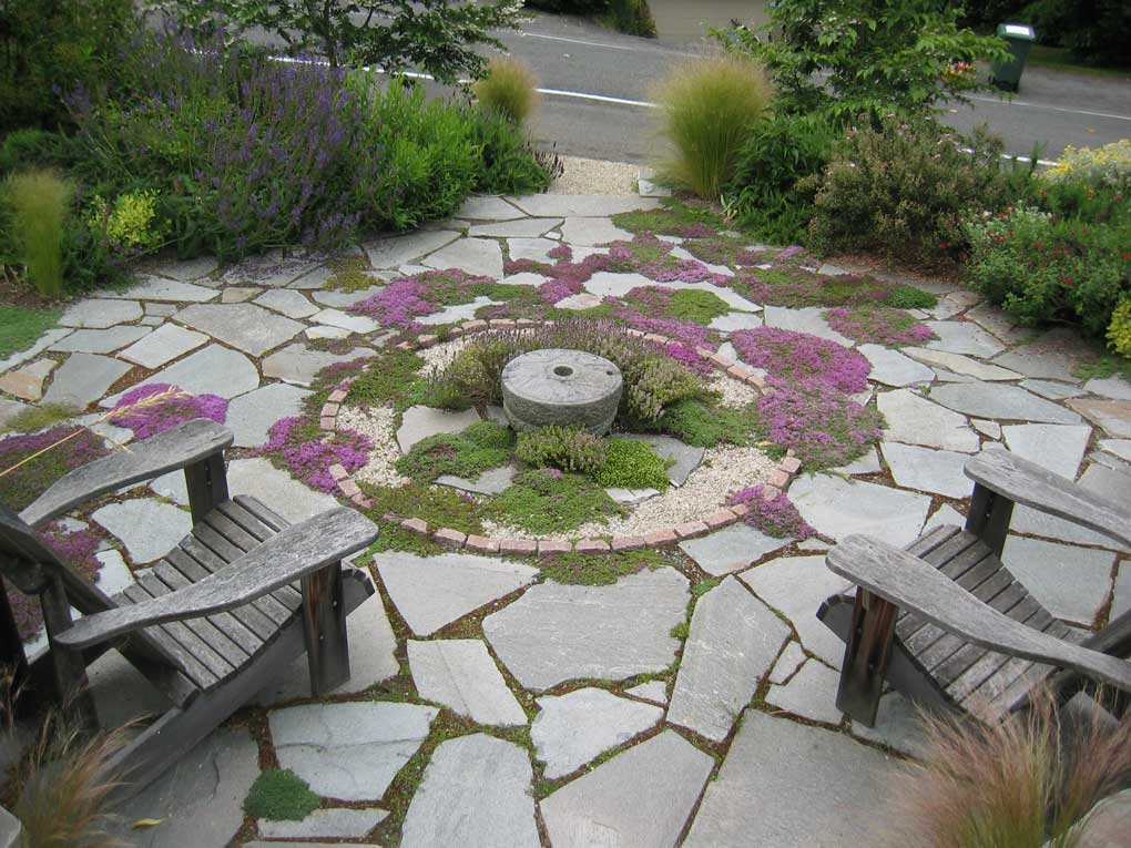 Stone paving creates a circular patio centering this Medierranean style garden
